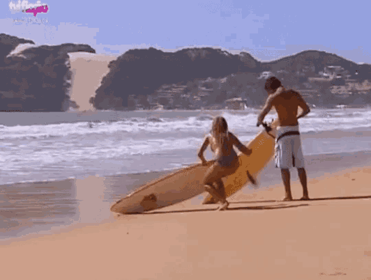 a man and a woman are standing on a beach with a surfboard and a sign that says netflix