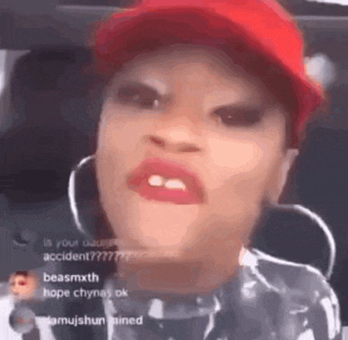 a close up of a woman wearing a red hat and hoop earrings making a funny face .