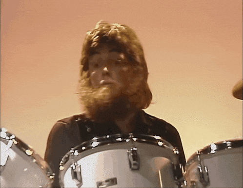 a man with a beard is playing a drum set with a yamaha logo on it
