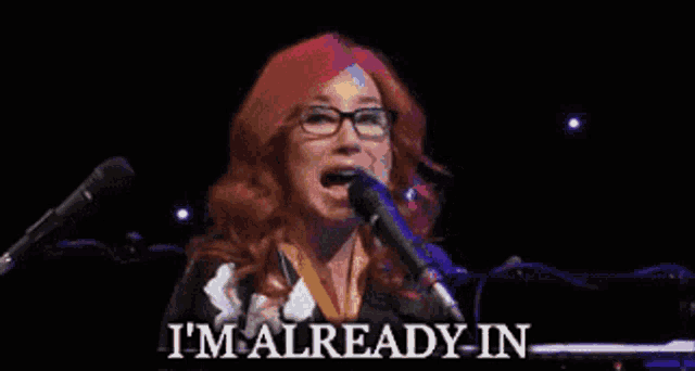 a woman singing into a microphone with the words " i 'm already in " below her