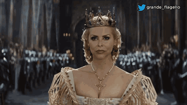 a woman wearing a crown and a necklace stands in front of a crowd with a twitter logo above her