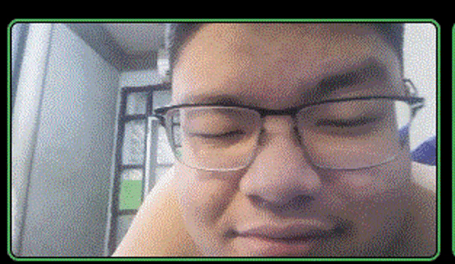 a man wearing glasses looks at the camera with his eyes closed