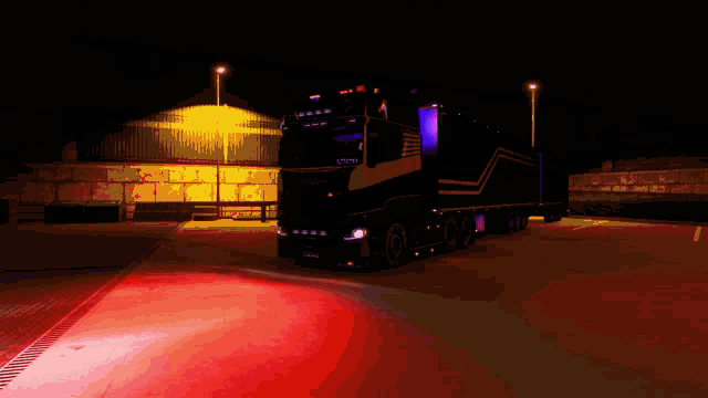a black scania truck is parked in a parking lot at night