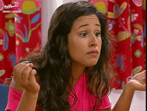 a woman in a pink shirt is sitting in front of a tv screen that says " tvi "
