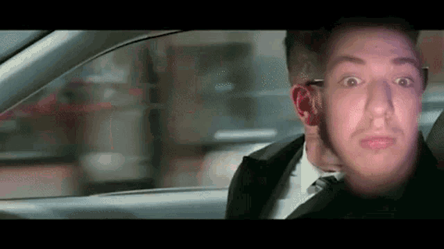 a man in a suit and tie is sitting in a car .