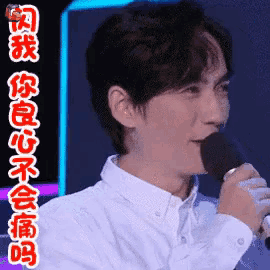 a man in a white shirt is singing into a microphone with chinese writing on it .