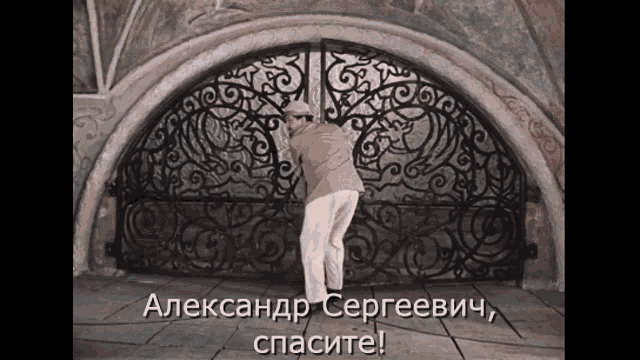 a man standing in front of a wrought iron gate with the words " александр сергеевич " written on the bottom