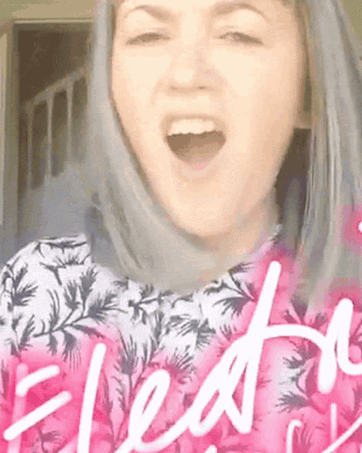 a woman wearing a pink and white floral shirt with the word electrifying written on it