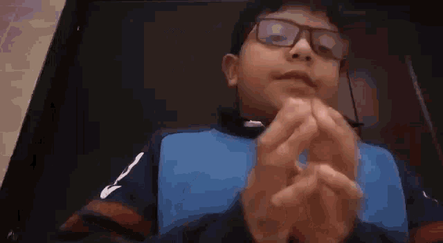 a boy wearing glasses is holding a piece of paper in his hands .