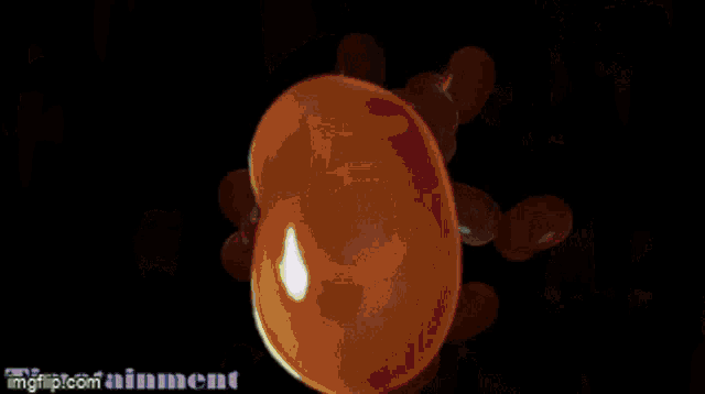 an orange ball is surrounded by green lines on a black background .