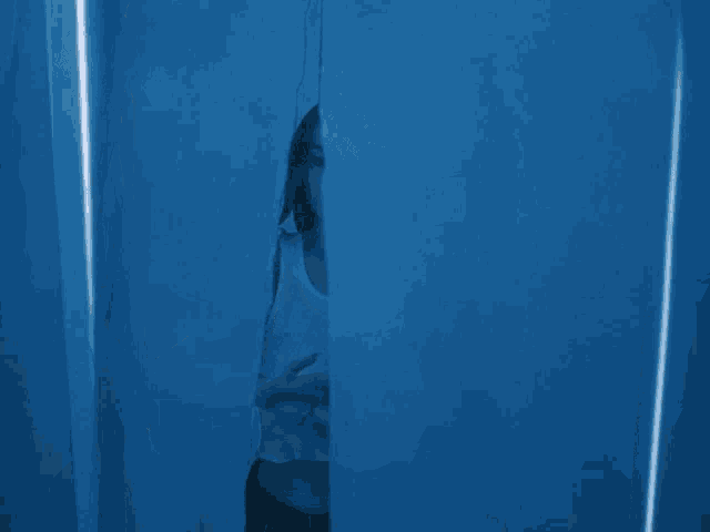 a woman in a white tank top stands in a dark room