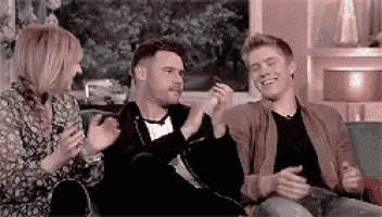 a group of people are sitting on a couch talking to each other and laughing .