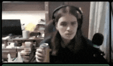 a woman wearing headphones is sitting in front of a microphone holding a can of soda .