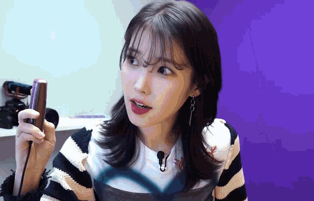 a woman in a striped sweater is holding a cell phone in her hand