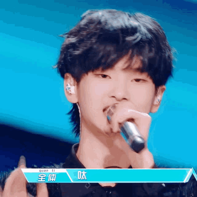 a young man singing into a microphone with the name quan ti written above him