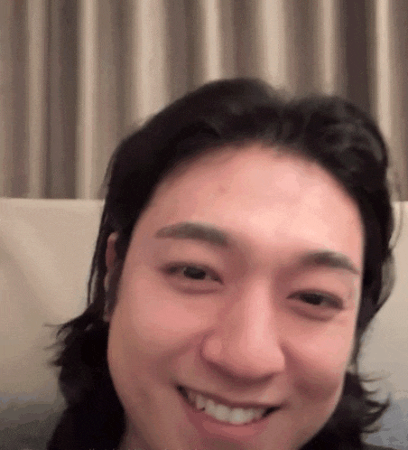 a man with long hair is smiling and looking at the camera .