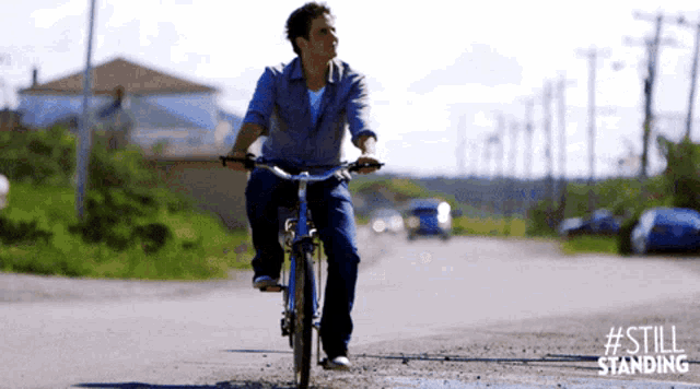 a man is riding a bike down a dirt road with #still standing written on the bottom