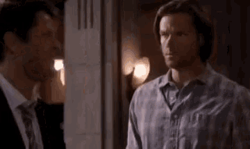 two men are standing next to each other in a room .