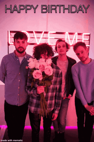 a group of men standing in front of a love me sign