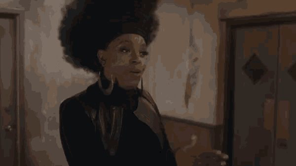 a woman with an afro is talking on a cell phone in a dark room .