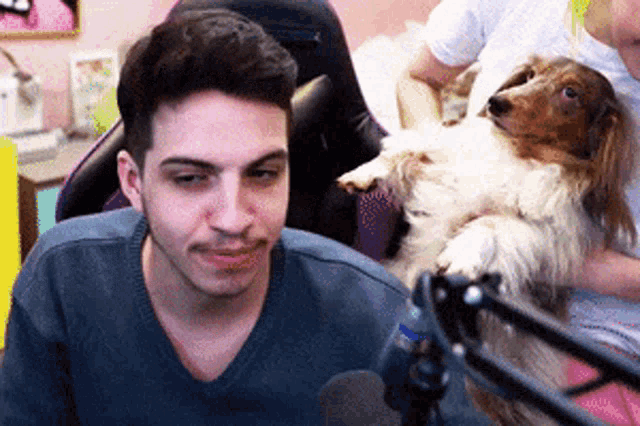 a man is holding a dachshund in his lap