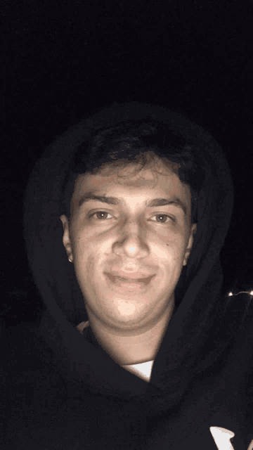 a young man wearing a black hoodie with a white letter k on it