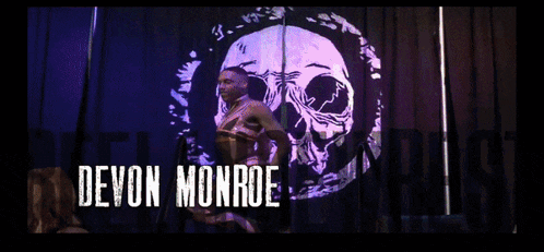 a man is standing in front of a skull on a black curtain