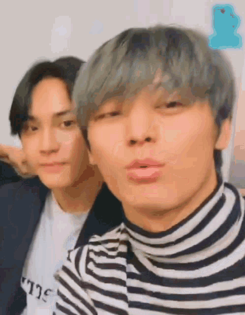 two young men are standing next to each other and making funny faces .