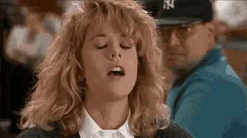 a woman is making a funny face with her mouth open and a man in a baseball cap behind her .