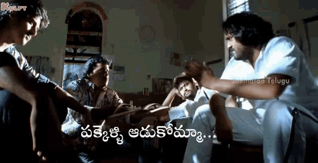 a group of people are sitting around a table in a room and talking in a foreign language .