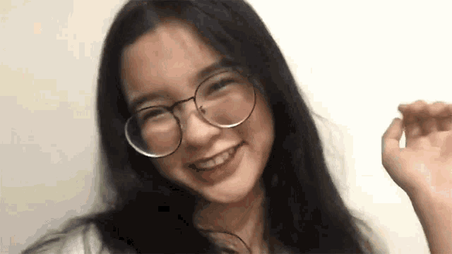 a young woman wearing glasses is smiling at the camera .