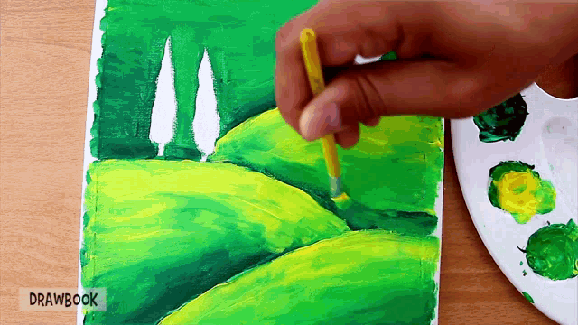 a person is painting a green and yellow landscape with drawbook written on the bottom