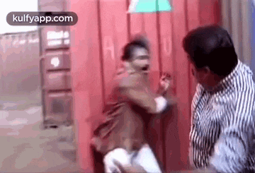 a man is fighting another man in front of a red wall .