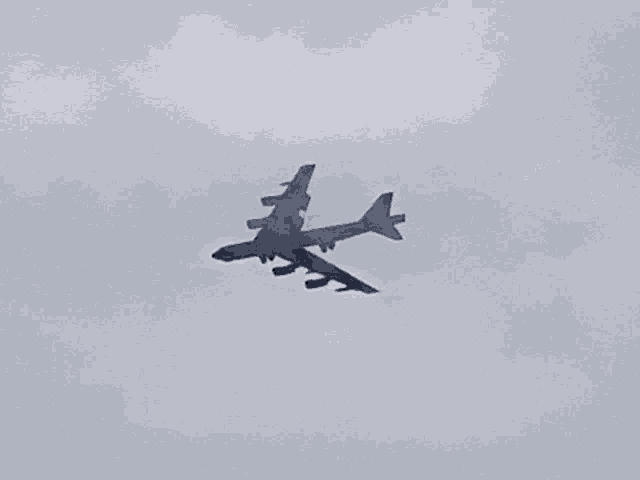 a plane flying through a cloudy sky with a shadow on the ground