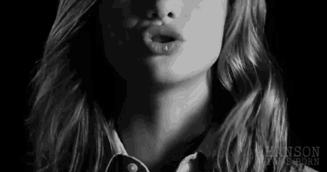 a black and white photo of a woman blowing a kiss .