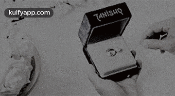 a black and white photo of a person holding a box with a ring in it .
