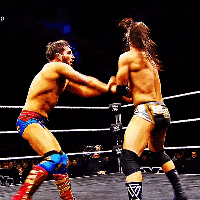 two men are wrestling in a ring with the letter w on the belt