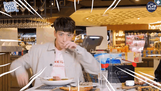 a man wearing a pink shirt that says nkil atelier eating food