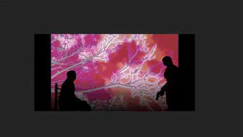 a silhouette of a man sitting in a chair and a man with a gun