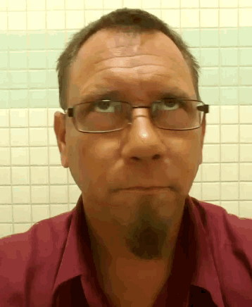 a man wearing glasses and a red shirt is making a face