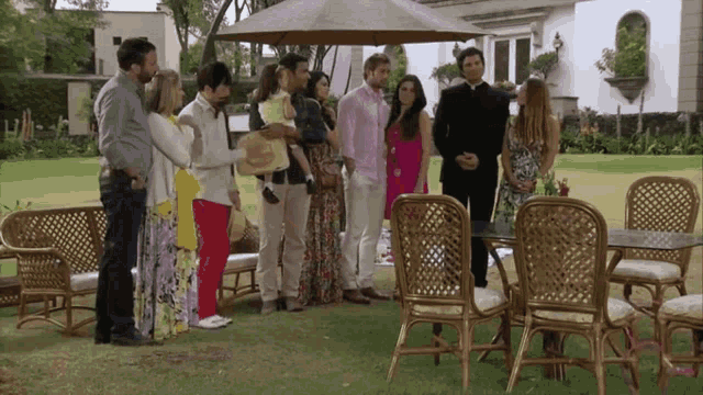 a group of people standing around a table in a garden