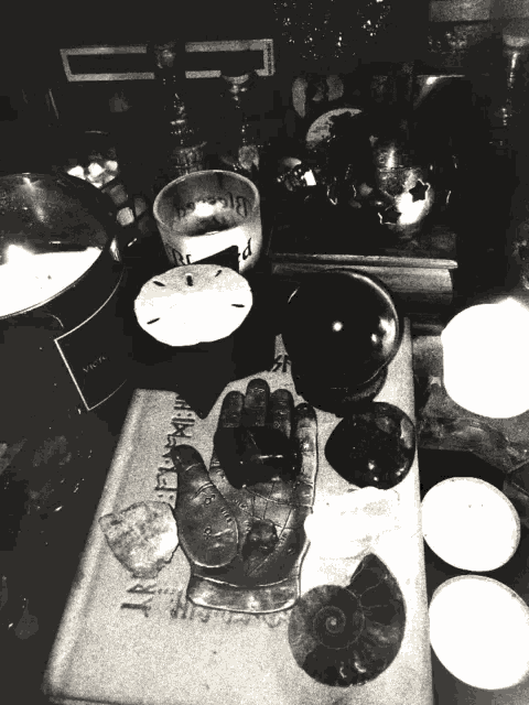 a black and white photo of a table with a hand and a book that says ' witchcraft ' at the top