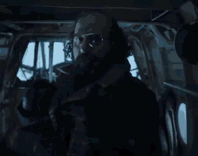 a man with a beard and glasses is sitting in a dark room