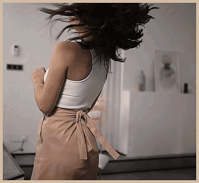 a woman wearing a white tank top and a tan skirt