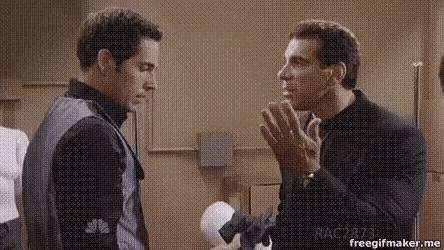 two men are standing next to each other in a room and talking .