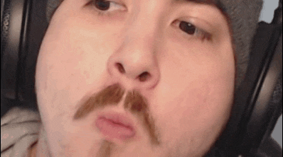 a close up of a man with a mustache wearing headphones and a hat .
