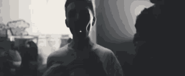 a black and white photo of a man in a white shirt standing in a room .