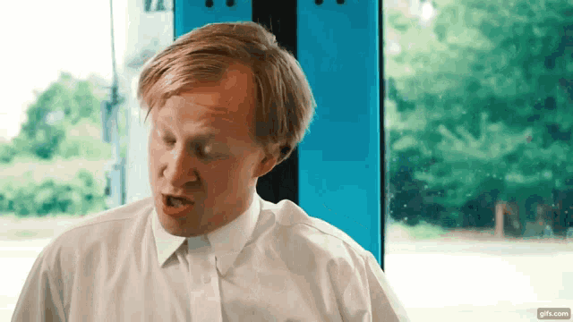 a man in a white shirt and tie is making a face