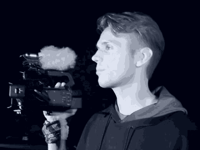 a black and white photo of a man holding a camera that says rode on it