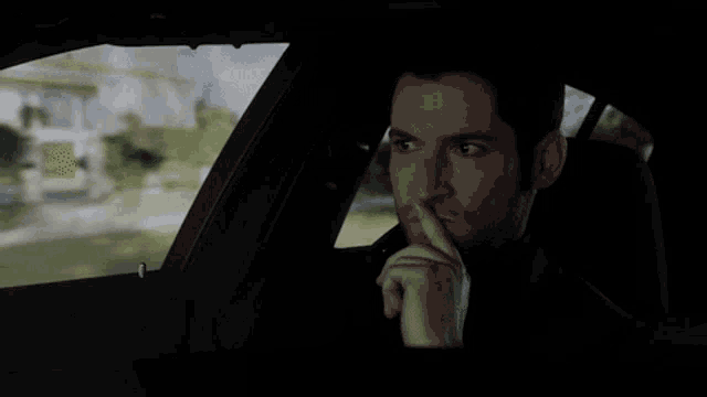 a man is sitting in a car with his finger to his mouth